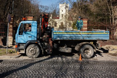 Lviv, Ukrayna - 07 Nisan 2025: Ukrayna 'nın Lviv kentindeki tarihi tuğla binanın yakınına park edilmiş mavi kamyonet.