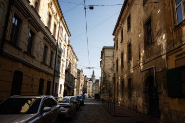 Lviv, Ukrayna - 07 Nisan 2025: Lviv 'de klasik mimari ve park halindeki araçlarla sakin bir kaldırım taşı caddesi.