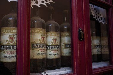 Lviv, Ukrayna - 07 Nisan 2025: Eski Porto şarabı Agdam şişeleri ahşap cam bir dolapta nostaljik bir ortamda