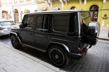 Lviv, Ukrayna - 07 Nisan 2025: Zarif siyah Mercedes-Benz G 63 AMG SUV Avrupa kentsel ortamında şehir kaldırımında duruyor.