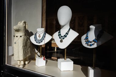 Renkli kolyeler vitrindeki doğal ışıklandırmalı manken boyunlarında sergileniyor..