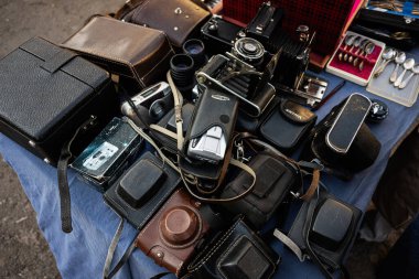 Lviv, Ukrayna - 07 Nisan 2025: Çeşitli retro kameralar ve davalar bir pazar yerinde mavi örtülü bir masaya vurgulandı.