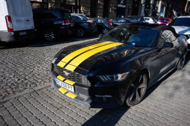 Lviv, Ukrayna - Nisan 07, 2025: Sarı çizgili Ford Mustang taştan bir kaldırım kenti caddesinde park edilmiş..