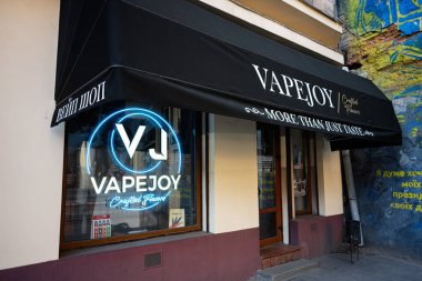 Lviv, Ukrayna - 07 Nisan 2025: VapeJoy mağaza vitrininde neon levha, el yapımı aroma markası ve sanatsal duvar grafitisi.