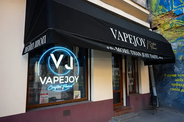Lviv, Ukrayna - 07 Nisan 2025: VapeJoy mağaza vitrininde neon levha, el yapımı aroma markası ve sanatsal duvar grafitisi.