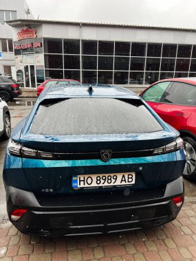 Kyiv, Ukrayna - 08 Nisan 2025: Binalar ve diğer araçlarla çevrili bir şehir parkında mavi bir Peugeot 408..