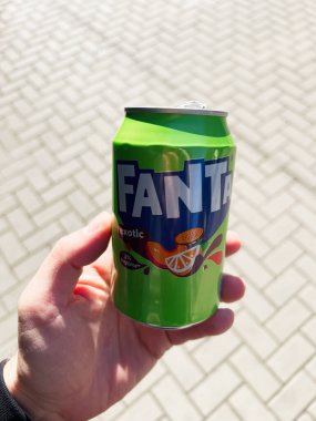 Kyiv, Ukrayna - 08 Nisan 2025: Fanta 'nın yeşil soda kutusunu güneş ışığında asfalt bir dış yüzeye tutan bir el