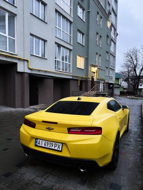 Kyiv, Ukrayna - 08 Nisan 2025: Parlak Chevrolet Camaro sarı spor araba bir yerleşim yerinin yanına park edilmiş. 