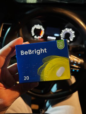 Kyiv, Ukrayna - 08 Nisan 2025: Parlak bir enstrüman paneli olan aracın içinde sakinleştirici ilaç paketi taşıyan kişi.