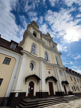 Buchach, Ukrayna - 08 Nisan 2025: Canlı mavi gökyüzü ve beyaz bulutlu tarihi bir kilise binası. Buchach Manastırı. Basilian Babalarının Kutsal Haçı 'nın Yüceliği.