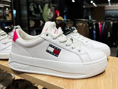 Kyiv, Ukrayna - 08 Nisan 2025: Modern bir perakende mağazasında renkli detaylarla sergilenen şık Tommy Hilfiger beyaz spor ayakkabıları