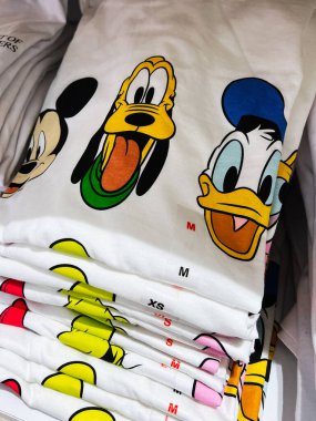Kyiv, Ukrayna - 08 Nisan 2025: Renkli animasyonlu grafiklerin sergilendiği katlanmış beyaz tişörtler. Donald Duck, Mickey Mouse ve Goofy. 