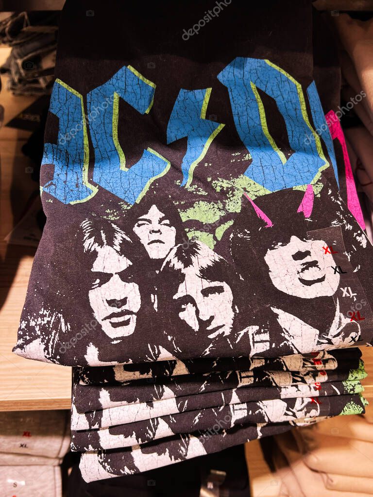 Kyiv, Ukraine - April 08, 2025: Stack of black graphic T-shirts featuring AC DC rock band artwork displayed on retail shelves