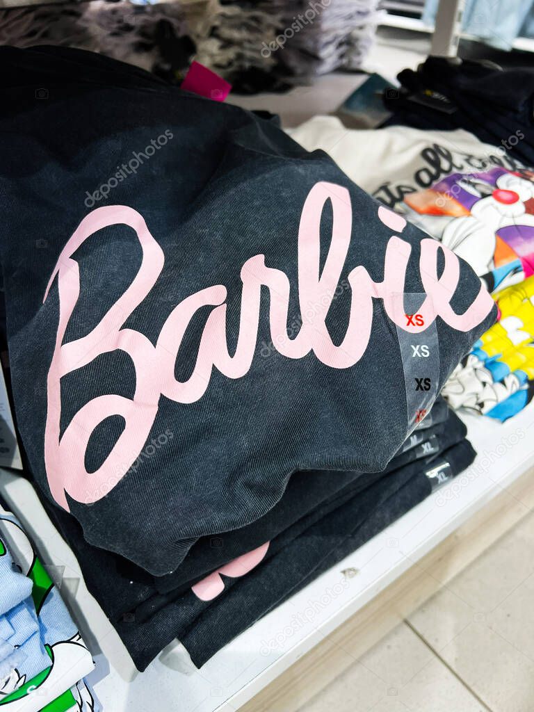 Kyiv, Ukraine - April 08, 2025: A set of neatly folded t-shirts showcasing Barbie trendy designs stacked on a shelf.