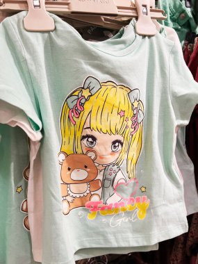 Kyiv, Ukrayna - 08 Nisan 2025: Pastel renkli çocuk tişörtü ve anime stili kız ve ayı tasarımı, bir askıda sergilendi