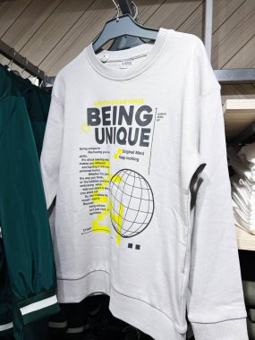 Kyiv, Ukrayna - 08 Nisan 2025: Motivasyonel metin gösteren beyaz sweatshirt Eşsiz ve grafikler, mağazadaki elbise rafında asılı.