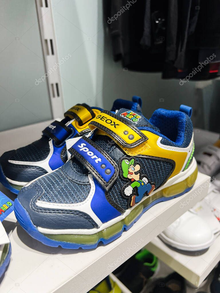 Kyiv, Ukraine - April 08, 2025: Vibrantly colored children sports shoes with Super Mario character figure displayed on store shelf.