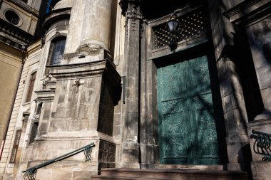 Tarihi Dominik Kilisesi cephesinde karmaşık yeşil kapılar ve Lviv 'de zamansız taş işçiliği yer alıyor..