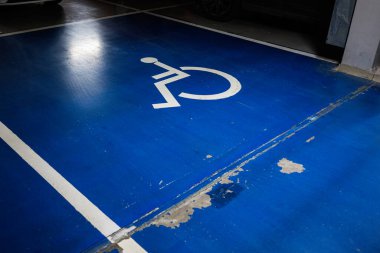 Otoparkın içinde erişilebilirlik logosu olan mavi engelli park yeri işaretli