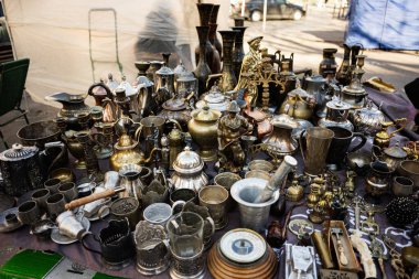 Assorted vintage utensils and antiques presented on a table at a street market clipart