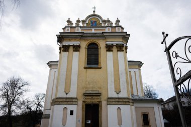 Buchach, Ukrayna - 08 Nisan 2025: Barok tarzı Bakire Meryem Varsayımı Kilisesi dramatik bulutlu bir arkaplan karşısında ayrıntılı ayrıntılarla