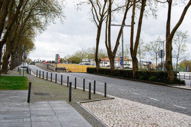 Fatima, Portekiz - 15 Nisan 2025: Fatima, Portekiz 'de park alanı yakınında ağaçlarla kaplı manzaralı bir cadde