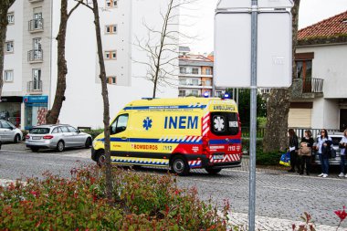 Fatima, Portekiz - 15 Nisan 2025: Fatima, Portekiz 'de konut ve ticari binaların yakınına park edilmiş bir şehir ambulansı