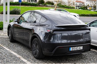 Fatima, Portekiz - 15 Nisan 2025: Portekiz 'in Fatima kentindeki kaldırım taşı yolda park etmiş modern elektrikli araç Tesla Model Y