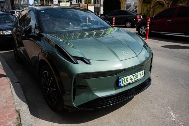 Khmelnytskyi, Ukrayna - 16 Nisan 2025: Çağdaş binaların bulunduğu kentsel bir sokağa park edilmiş yeşil elektrikli Zeekr X aracı