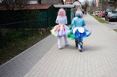 Khmelnytskyi, Ukrayna - 16 Nisan 2025: Aydınlık bir günde neşeli, renkli kostümler içinde yürüyüş yapan iki eğlenceli kişi