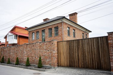 Khmelnytskyi, Ukrayna - 16 Nisan 2025: Duvarla çevrili tuğla bir ev ve ahşap kapı manzarası.