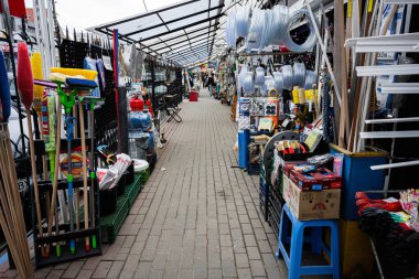 Khmelnytskyi, Ukrayna - 16 Nisan 2025: Süpürgeler, borular ve hizmet malzemelerinin yer aldığı donanım malzemeleri ile dar pazar koridoru
