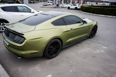 Khmelnytskyi, Ukrayna - 16 Nisan 2025: Otoparkta çeşitli araçlarla çevrili şık Ford Mustang GT yeşil spor araba