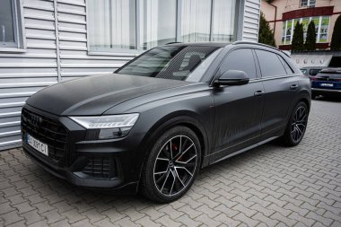 Khmelnytskyi, Ukrayna - 16 Nisan 2025: Sportif mat siyah Audi Q8 çağdaş bir binanın önünde park edilmiş şık jantlar