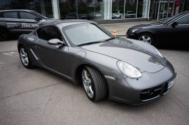 Khmelnytskyi, Ukrayna - 16 Nisan 2025: Açık havada diğer araçların yanına park edilmiş parlak gri bir Porsche Cayman arabası.