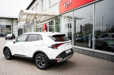 Khmelnytskyi, Ukrayna - 16 Nisan 2025: Beyaz Kia Sportage SUV kaldırımlı bir otoparkta araba galerisi binasından önce sergilendi