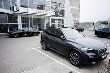Khmelnytskyi, Ukrayna - 16 Nisan 2025: SUV ve sedan BMW modelleri cam cepheli bir galerinin önünde park halindeler..