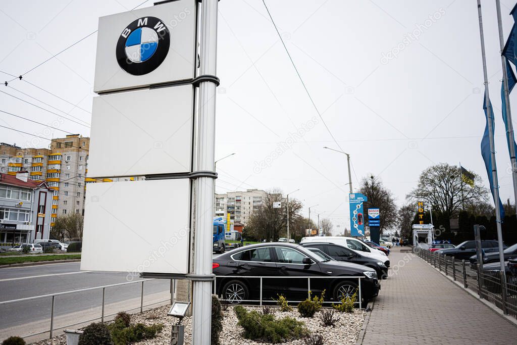 Khmelnytskyi, Ukraine - April 16, 2025: Urban street view featuring a BMW dealership and cars in a landscaped parking area