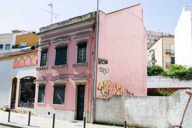 Caldas da Rainha, Portekiz - 17 Nisan 2025: Grafiti ile iki katlı pembe bina, kapalı panjurlar, Portekiz 'in bir kentsel bölgesinde yer alıyor.