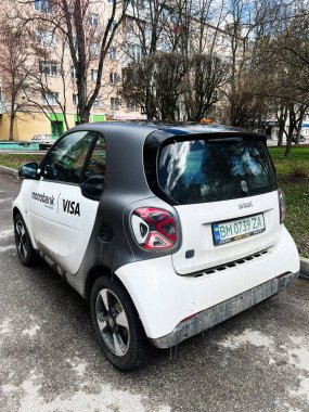 Kyiv, Ukrayna - 23 Nisan 2025: Modern bir kompakt araç Smart ForTwo EQ ile kentsel konut alanının yakınına park edilmiş reklamlar.