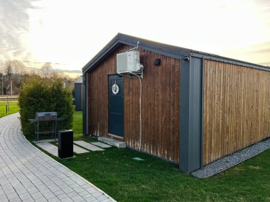 Okhrymivtsi, Ukrayna - 23 Nisan 2025: Klimalı ve parktaki yeşilliklerle çevrili ahşap bir kulübe.