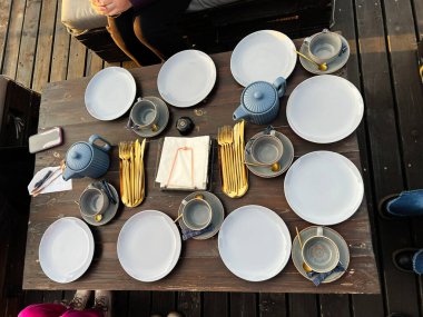Tabaklar, fincanlar, altın çatal bıçak takımı ve çaydanlık.