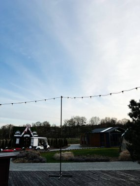 Okhrymivtsi, Ukrayna - 23 Nisan 2025: Mevsimlik dekorasyonlar, parlak sicim ışıkları ve açık mavi gökyüzü ile manzaralı park