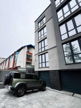 Kyiv, Ukrayna - 23 Nisan 2025: Geniş pencereli bir şehir konutu ve park halindeki yeşil araç Land Rover Defender aracı