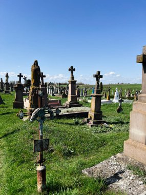 Khorostkiv, Ukrayna - 23 Nisan 2025: Yıpranmış taş haçlar ve canlı yeşil otların yer aldığı sakin tarihi bir mezarlık.