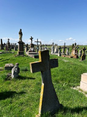 Khorostkiv, Ukrayna - 23 Nisan 2025: Açık bir gökyüzünün altında çimlerle çevrili yıpranmış taşlarla dolu sakin bir mezarlık sahnesi
