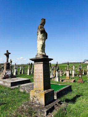 Khorostkiv, Ukrayna - 23 Nisan 2025: Mavi gökyüzünün altındaki eski bir mezarlıkta yıpranmış bir heykel.