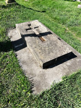 Khorostkiv, Ukrayna - 23 Nisan 2025: Güneş ışığıyla çevrili bir haç içeren yıpranmış bir taş mezar taşı.