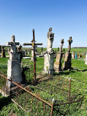 Khorostkiv, Ukrayna - 23 Nisan 2025: Kırsal bir mezarlığın ortasındaki demir çitle çevrili yıpranmış mezar işaretleri.