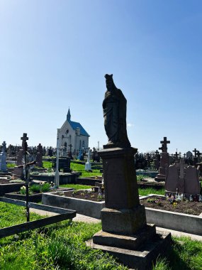 Khorostkiv, Ukrayna - 23 Nisan 2025: Mezarlıktaki taş heykel mezarlıklar, haçlar ve dingin bir şapelle çevrili